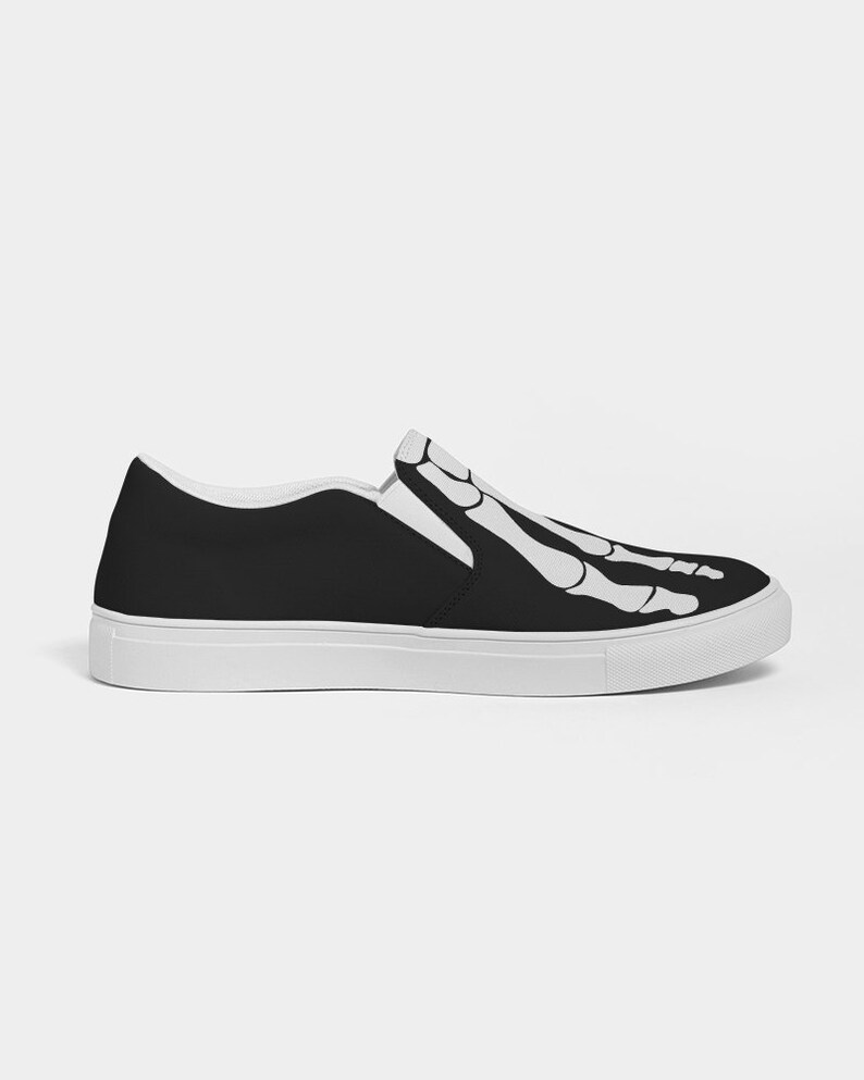 May include: Black slip-on canvas shoes with a white skeleton foot design.