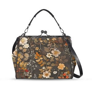 May include: A floral print handbag with a black handle and shoulder strap. The bag features a dark background with a pattern of white, orange, and yellow flowers and foliage. The clasp is a decorative metal design.