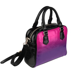 May include: A black satchel handbag with a pink to purple ombre design. The bag has a top zipper closure, two top handles, and a detachable shoulder strap.