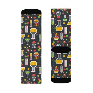 May include: A pair of black socks with a colorful pattern of beakers, test tubes, and other science-related imagery. The socks are designed for adults.