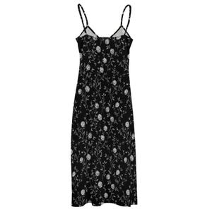 May include: A black midi dress with thin spaghetti straps. The dress is covered in a white floral pattern. The dress has a V-neckline and a straight, flowing silhouette. The dress is made of a lightweight fabric.