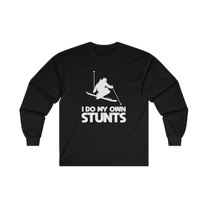 Op de afbeelding: Zwart shirt met lange mouwen en een witte afbeelding van een skiër in actie, met de tekst "I DO MY OWN STUNTS". Het shirt is gemaakt van een zacht materiaal, geschikt voor dagelijks gebruik.