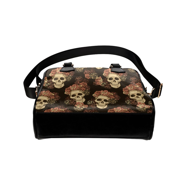 May include: A black leather handbag with a shoulder strap. The bag has a floral pattern with skulls and roses.