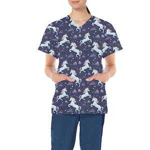 Puede incluir: Una blusa de trabajo azul marino con un patrón de unicornios blancos y nubes sobre un fondo azul oscuro. La blusa de trabajo tiene cuello en V y mangas cortas.