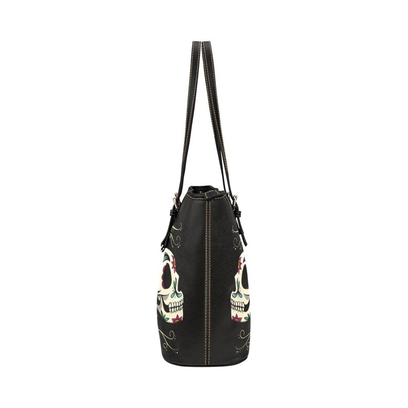 May include: Black tote bag with two sugar skull designs on the front. The skulls are white with colorful floral details.