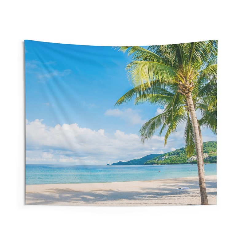 May include: A tapestry featuring a tropical beach scene with two palm trees in the foreground, a white sandy beach, and a turquoise ocean. The sky is a bright blue with fluffy white clouds.