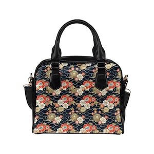 May include: A black leather handbag with a floral pattern. The pattern features red, white, and gold flowers on a black background. The bag has a top handle and a shoulder strap.