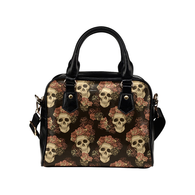 May include: A black handbag with a skull and rose pattern. The bag has a top handle and a shoulder strap.