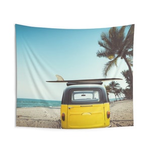 May include: A yellow vintage van with a surfboard on top parked on a sandy beach with palm trees in the background.