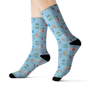 May include: A pair of blue socks with a pattern of medical supplies, including bandages, pills, stethoscopes, and first aid kits.