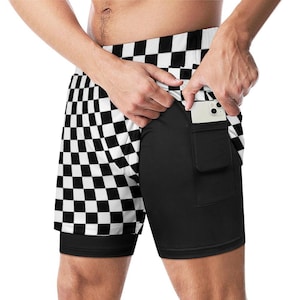 Puede incluir: Pantalones cortos deportivos a cuadros blancos y negros con una capa de compresión negra incorporada. Los pantalones cortos tienen un bolsillo en el lado derecho, que contiene un teléfono inteligente blanco. La capa exterior presenta un patrón de tablero de ajedrez.