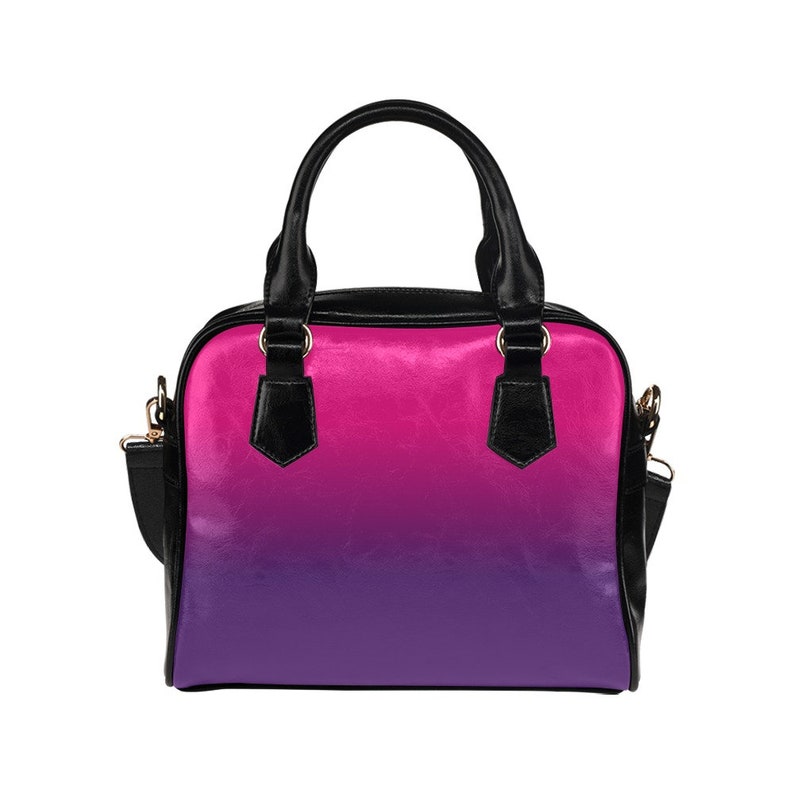 May include: A small black handbag with a pink to purple ombre design. The bag has a top handle and a shoulder strap.