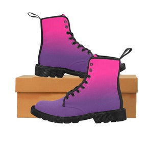 May include: A pair of black lace-up boots with a pink to purple ombre design. The boots are sitting on a brown box.