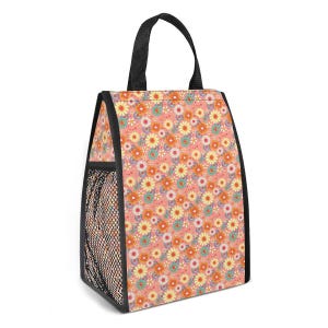 Könnte beinhalten: Eine Lunchtasche mit Blumenmuster und schwarzem Griff und Besatz. Die Tasche hat ein sich wiederholendes Muster aus bunten Blumen auf pfirsichfarbenem Hintergrund. Eine schwarze Netztasche ist an der Seite sichtbar.