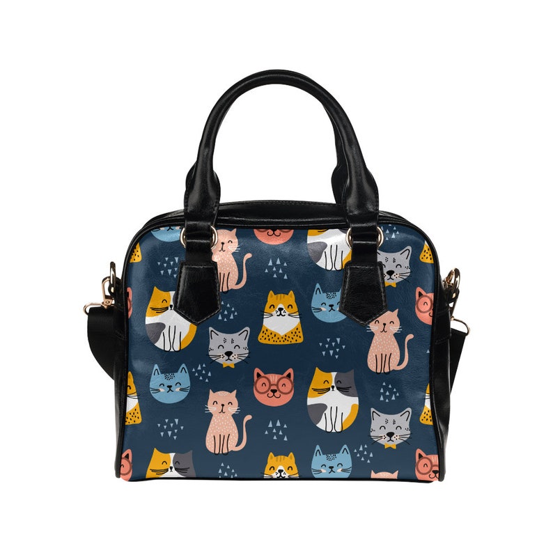 May include: A black handbag with a blue background and a repeating pattern of colorful cats. The cats are in various poses and have different facial expressions.