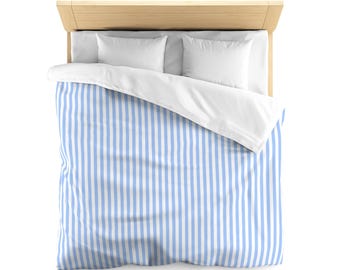 May include: Overhead view of a bed with a light wood headboard, two white pillows, and a duvet cover with vertical blue and white stripes. The bed is neatly made, creating a clean and inviting aesthetic. The bedding is a light blue and white color.