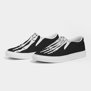 May include: A pair of black slip-on canvas shoes with a white skeleton foot design.