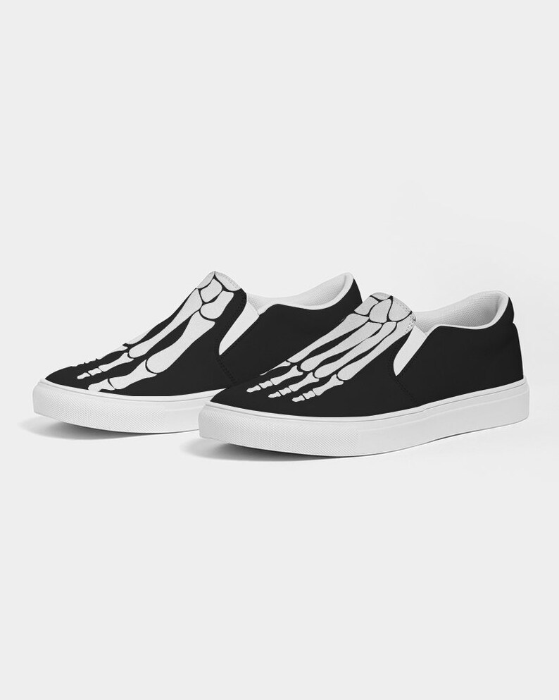 May include: A pair of black slip-on canvas shoes with a white skeleton foot design.