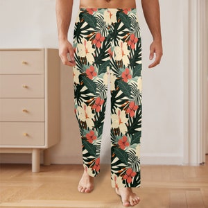 May include: Tropical print pyjama trousers with a cream background, featuring green leaves, pink and white flowers.