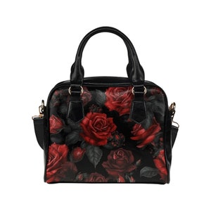 May include: Black handbag with a red rose floral print. The bag has a top handle and a shoulder strap.