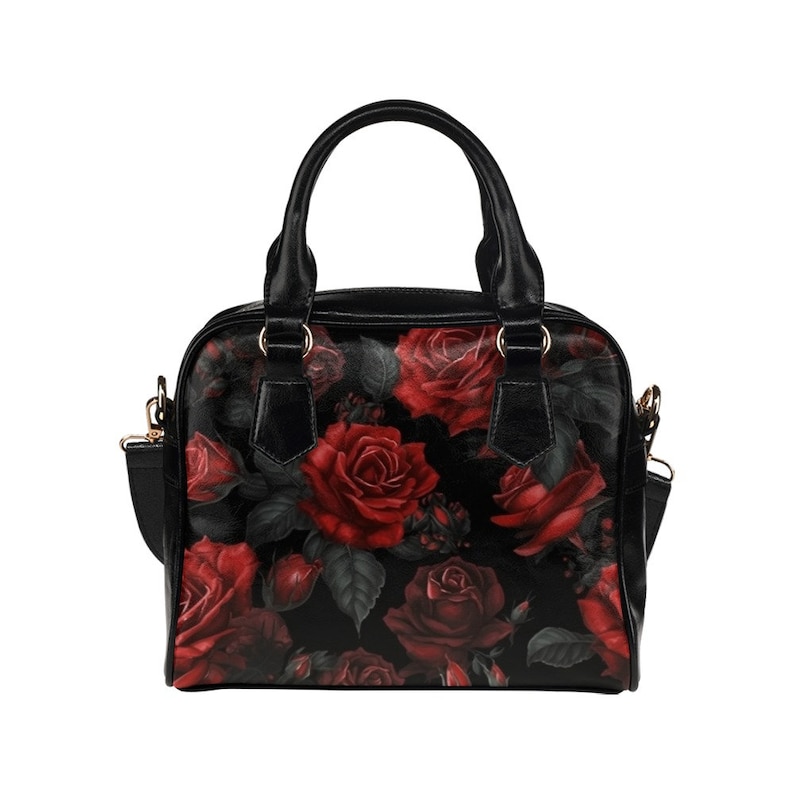 May include: Black handbag with a red rose floral print. The bag has a top handle and a shoulder strap.