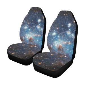 May include: A pair of black car seat covers with a galaxy print featuring a blue background with white and yellow stars.