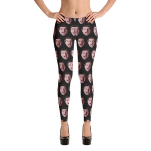 May include: Black leggings featuring a repeating pattern of a person's face. The faces are in various expressions, with open mouths and surprised looks. The leggings are worn with black platform heels.