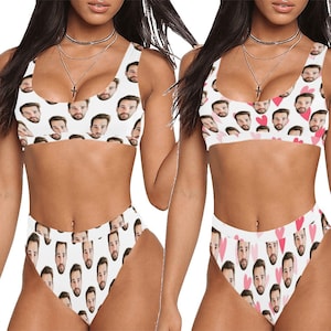 May include: Two white bikini tops and bottoms with a repeated pattern of a man's face. One bikini has pink hearts in the pattern.