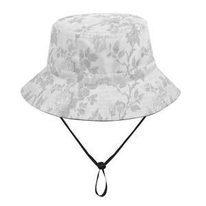 May include: A white bucket hat with a floral pattern in shades of gray. The hat has a black chin strap with an adjustable toggle. The brim is wide and the hat is made of a lightweight fabric.