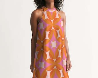 May include: A sleeveless halter dress with a geometric pattern in shades of orange, pink, and white. The dress has a loose fit and a slightly flared hem.