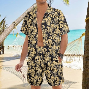 May include: A black and gold patterned short-sleeved shirt and matching shorts set. The shirt has a collar and a button-up front. The shorts have an elastic waistband.
