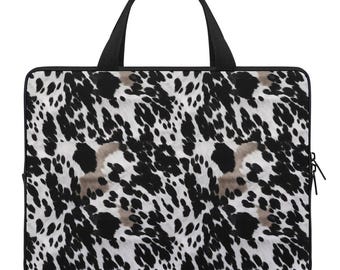 May include: Black and white laptop bag with a spotted animal print design. The bag has a black handle and a zipper closure.