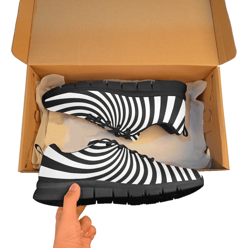 May include: A pair of black and white sneakers with a spiral pattern. The sneakers are in a cardboard box.