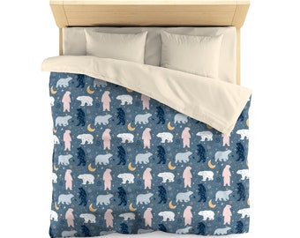 May include: A blue duvet cover with a repeating pattern of white, pink, and blue polar bears and crescent moons. The duvet cover is on a bed with white pillowcases.