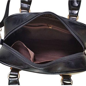 May include: Black leather satchel bag with a zipper closure and gold hardware. The bag has a top handle and a shoulder strap.