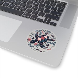 May include: A sticker featuring a stylized illustration of a sea turtle surrounded by various sea life, including starfish, seashells, and seaweed. The turtle is blue and pink with a white shell.