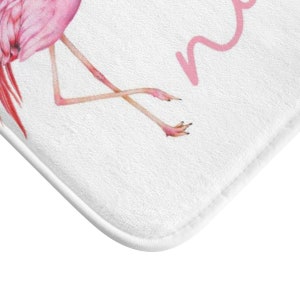 May include: Pink flamingo bath mat with the word "namaste" written in pink cursive.
