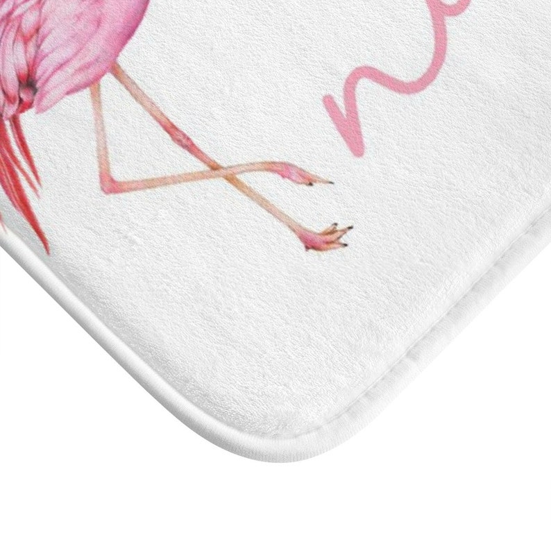 May include: Pink flamingo bath mat with the word "namaste" written in pink cursive.