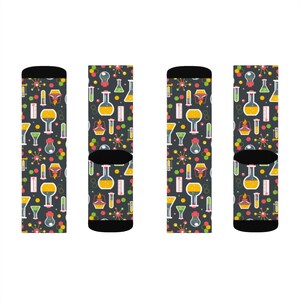 May include: Four pairs of black socks with a colorful science themed pattern. The pattern includes beakers, test tubes, and other lab equipment.