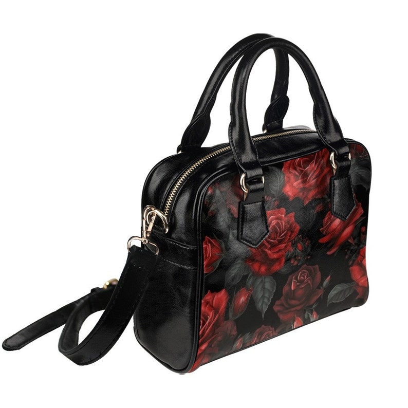 May include: A black handbag with a red rose floral print. The bag has a top zipper closure, two top handles, and a detachable shoulder strap.