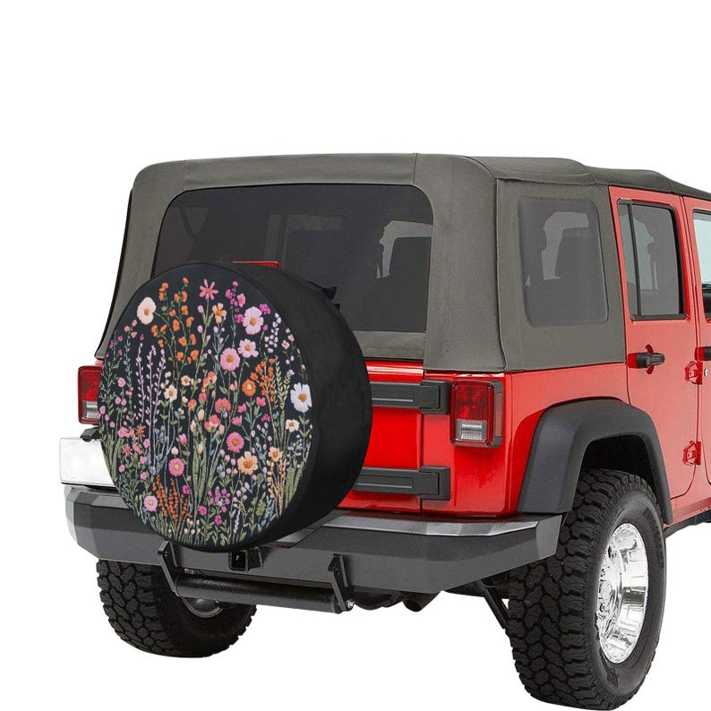 May include: A red Jeep Wrangler with a black spare tire cover featuring a floral pattern. The spare tire cover has a black background with colorful flowers and leaves.