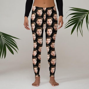 May include: Black leggings featuring a repeating pattern of a man's face. The faces are evenly spaced across the fabric. The leggings are worn by a person with a black long-sleeve shirt.