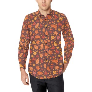 Op de afbeelding: Een button-down overhemd met lange mouwen met een bruine achtergrond en een herhalend patroon van oranje, gele en rode herfstbladeren, eikels en kleine bloemen. Het overhemd is gemaakt van een lichte stof.