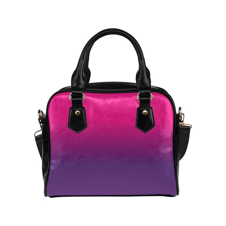 May include: A black handbag with a pink to purple ombre design. The bag has a top handle and a shoulder strap.