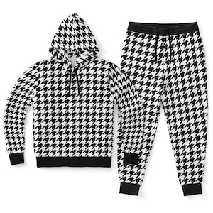 Pode incluir: Um conjunto de moletom com capuz e calças de moletom com estampa de pata de galinha em preto e branco. O moletom com capuz tem um cordão e um capuz. As calças de moletom têm um cordão e punhos elásticos. O conjunto é feito de um material macio e confortável.