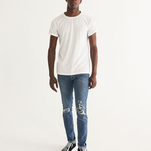 May include: A person wearing a white t-shirt, blue jeans with distressed details, and black and white skeleton-themed sneakers.