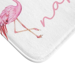 May include: Pink flamingo bath mat with the word "mama" written in pink cursive.