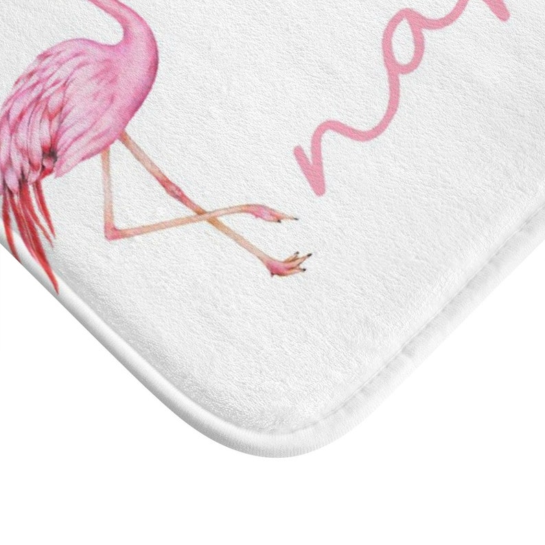 May include: Pink flamingo bath mat with the word "mama" written in pink cursive.