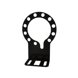 May include: Black metal gauge mount with a circular cutout and multiple holes around the edge. The mount has a bracket with three slots for mounting.