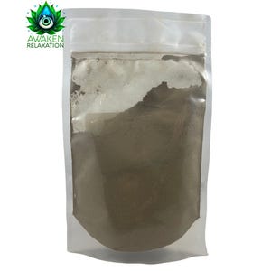 Puede incluir: Una bolsa de pl&aacute;stico transparente con base, llena de un polvo fino de color marr&oacute;n claro. La parte superior de la bolsa cuenta con un cierre herm&eacute;tico. En la esquina superior izquierda, un logotipo muestra una flor de loto verde con un ojo azul y el texto AWAKEN RELAXATION.